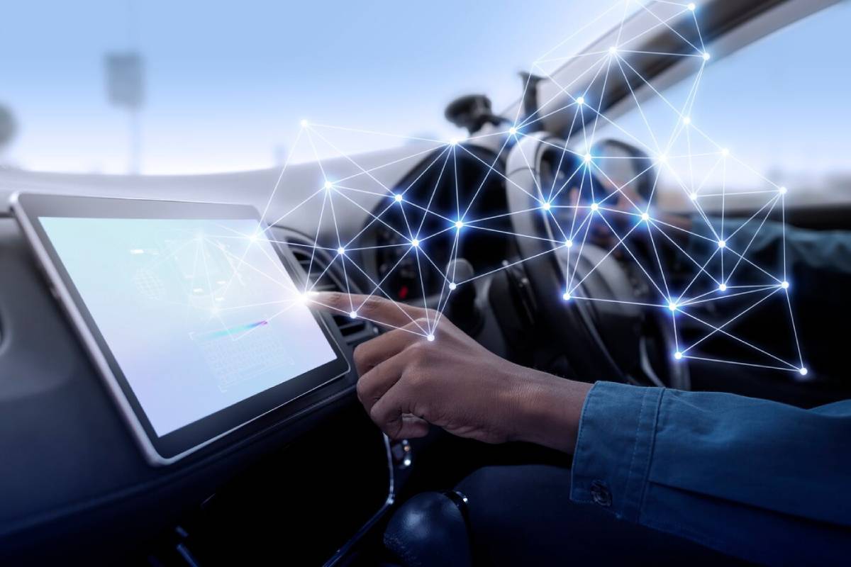 A person operating a vehicle with a tablet displaying futuristic, interactive connectivity graphics.