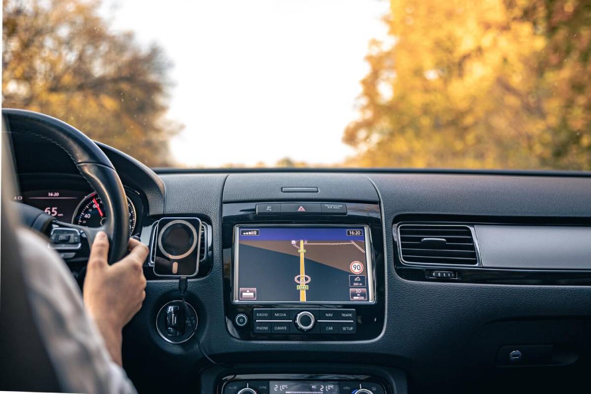 Driver's view inside a car showing the steering wheel and a navigation screen with a road map.