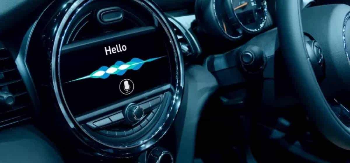 Close-up of a car dashboard displaying a voice assistant interface with a greeting "Hello" and sound wave visualizations.