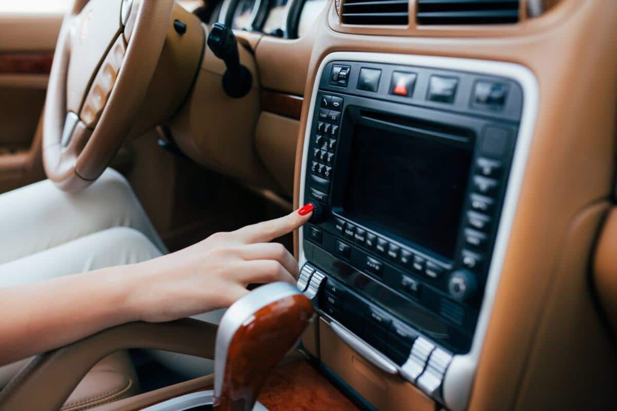 A close-up of a woman's hand with red nails, adjusting the car's modern
