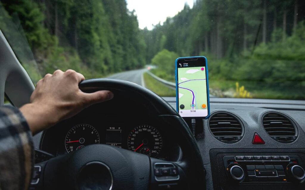 Driver's perspective using a smartphone GPS on a forest road trip.